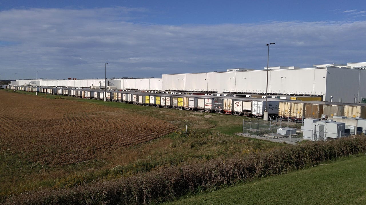 A long white warehouse with a line of trailers along its docks