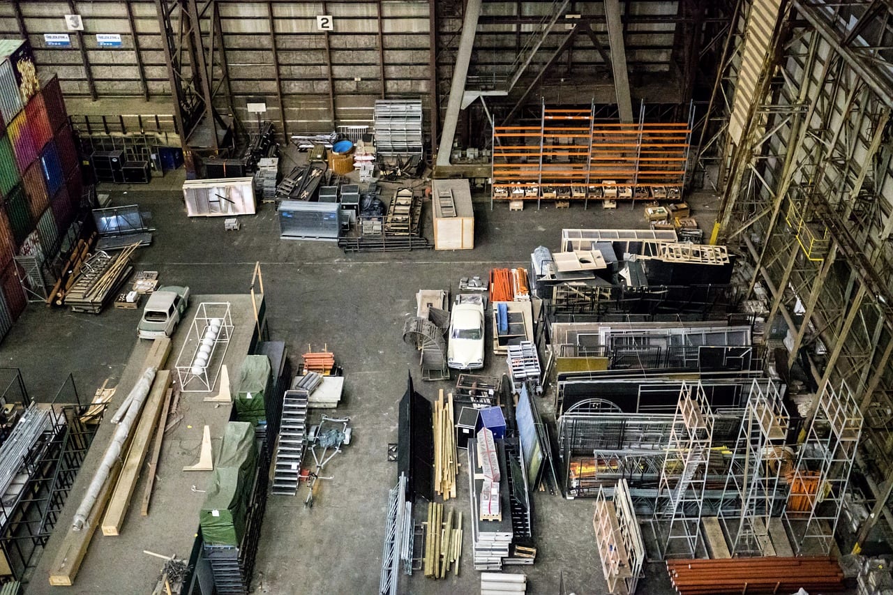 A storage hall floor seen from above, crowded with racks, scaffolding and stock