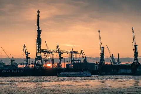 Harbor cranes along a waterfront at sunset