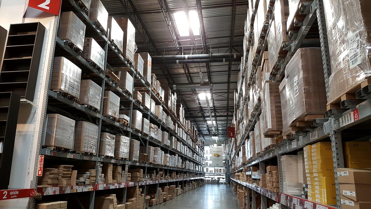 A warehouse aisle lined with racked cartons under strip lights