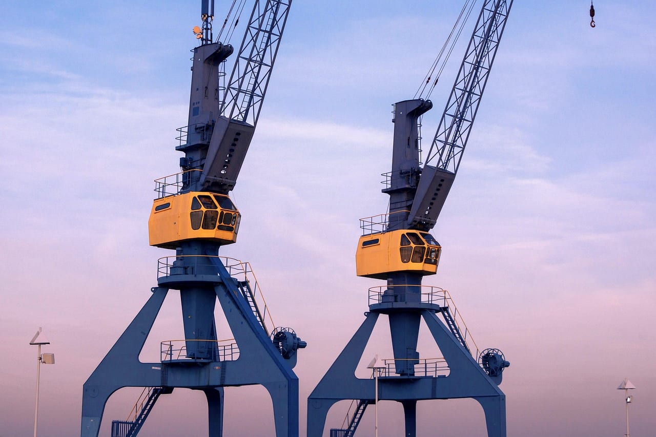 Two harbor cranes against a violet evening sky