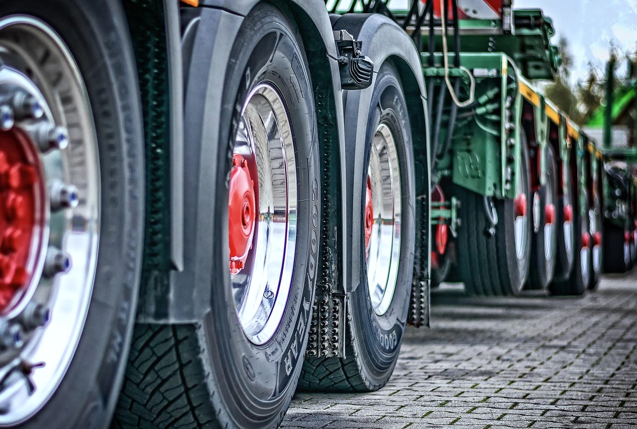 The wheels of a row of heavy trucks, chrome hubs catching the light