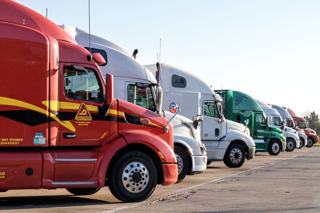 A row of parked semi tractors, cabs lined up nose to tail