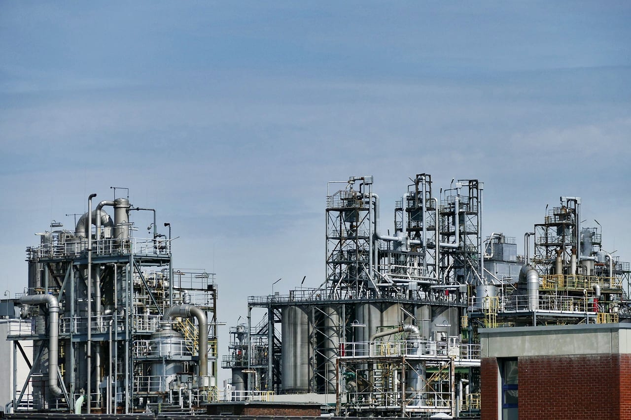 The towers and pipework of a refinery under an overcast sky