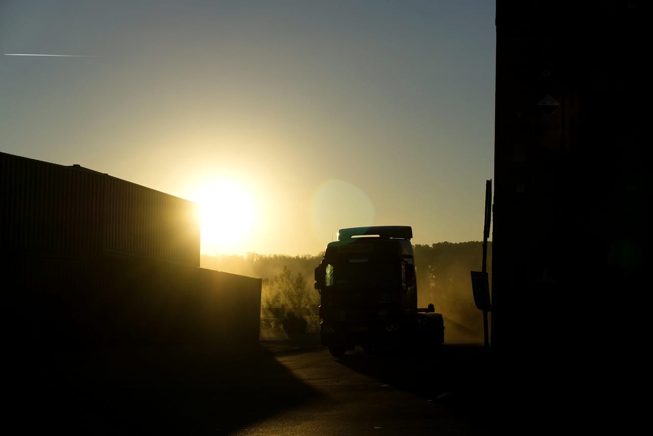 A truck in silhouette against a low sun in a freight yard