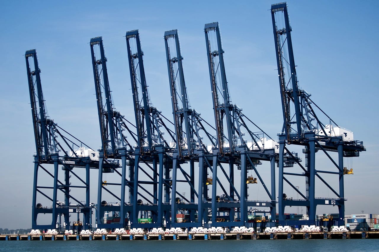 A row of blue gantry cranes along a quay