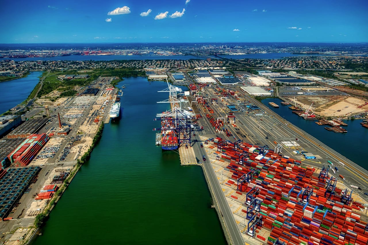 A container port from the air, quays lined with red cranes