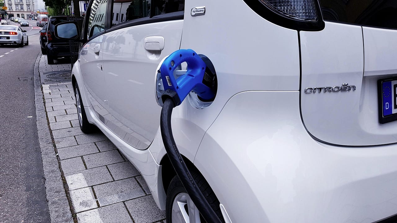 A charging cable plugged into a white electric vehicle