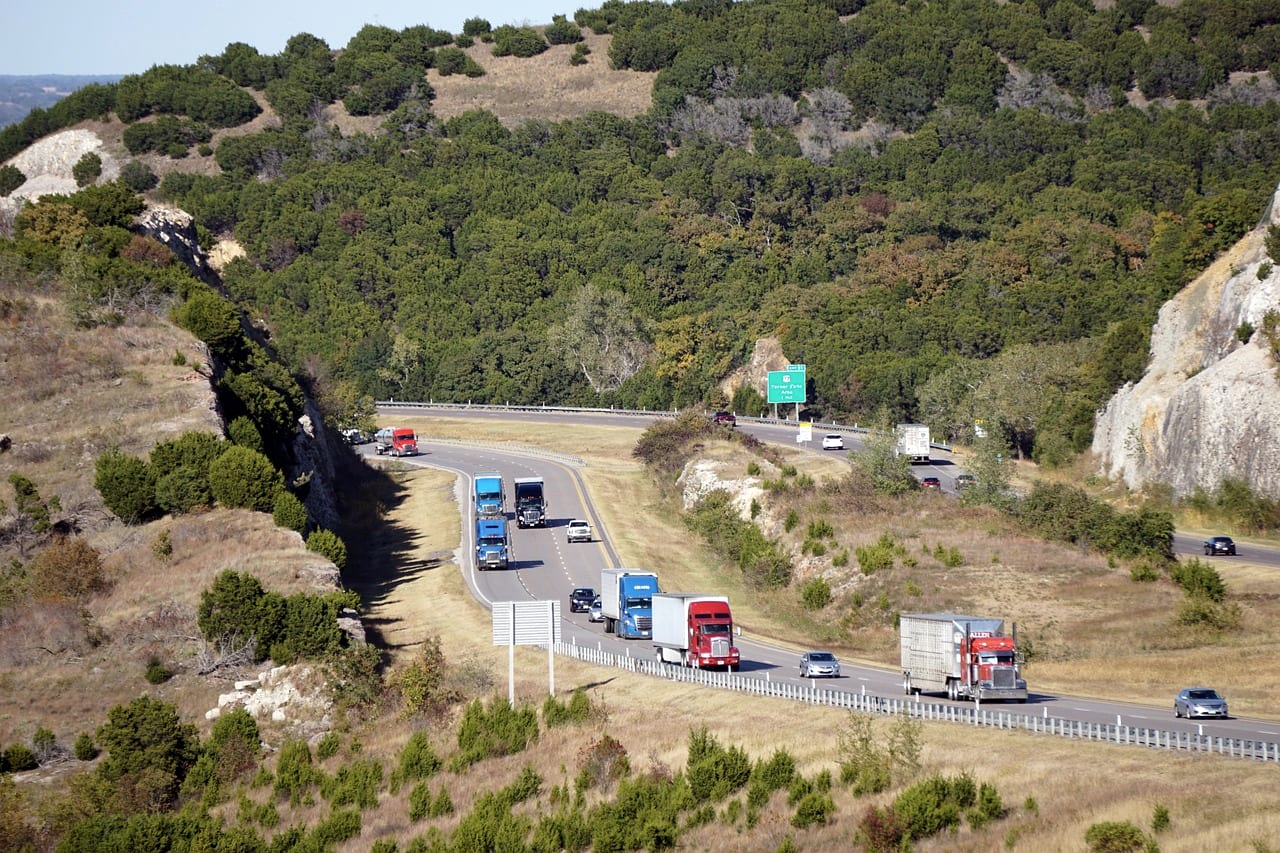 Trucks and cars on a four-lane highway cut through dry hills