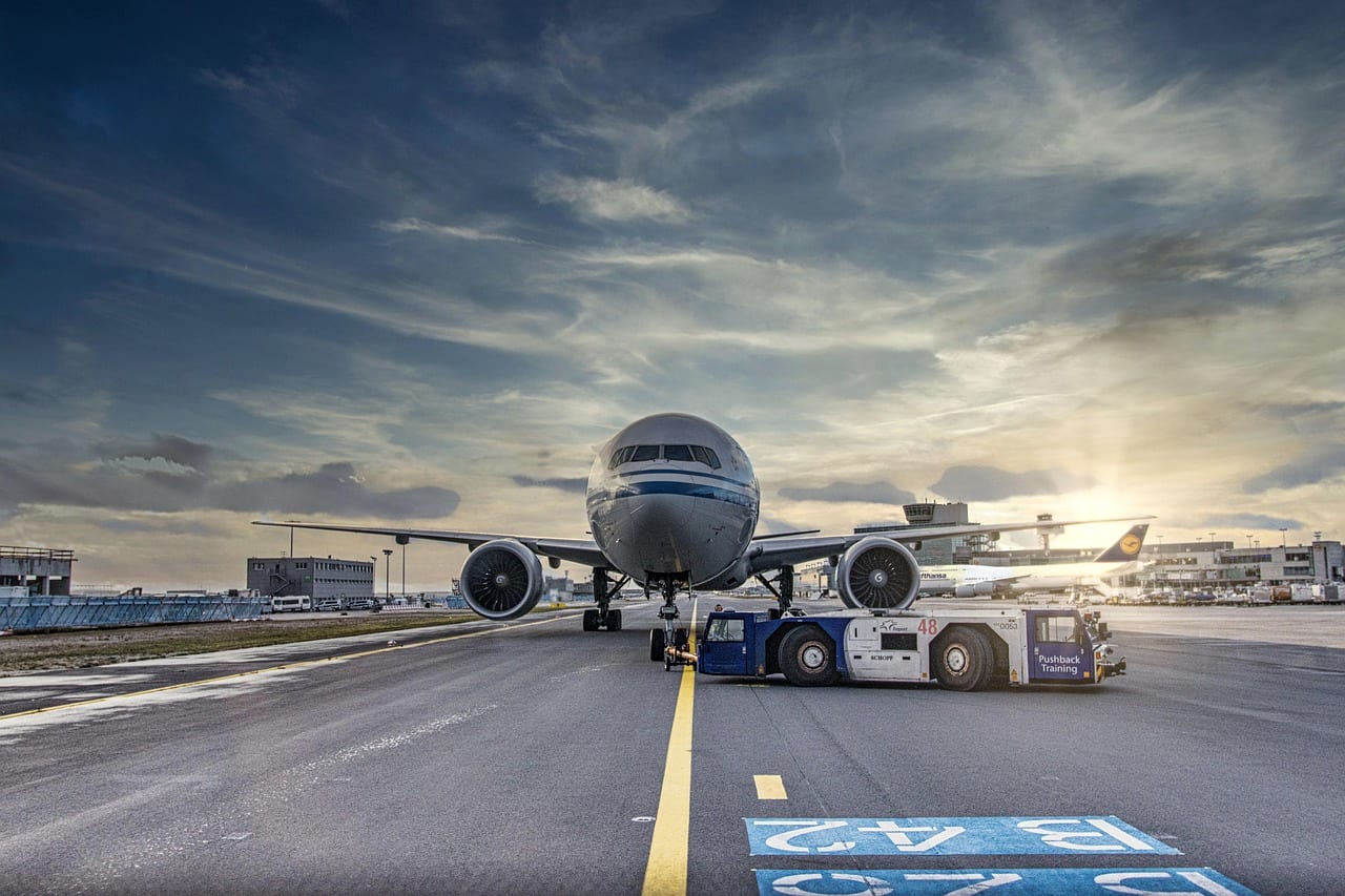 A wide-body aircraft under tow on a taxiway at sunrise