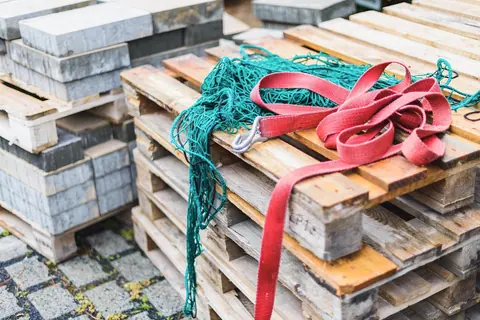 Lashing straps and a cargo net lying on a stack of used pallets