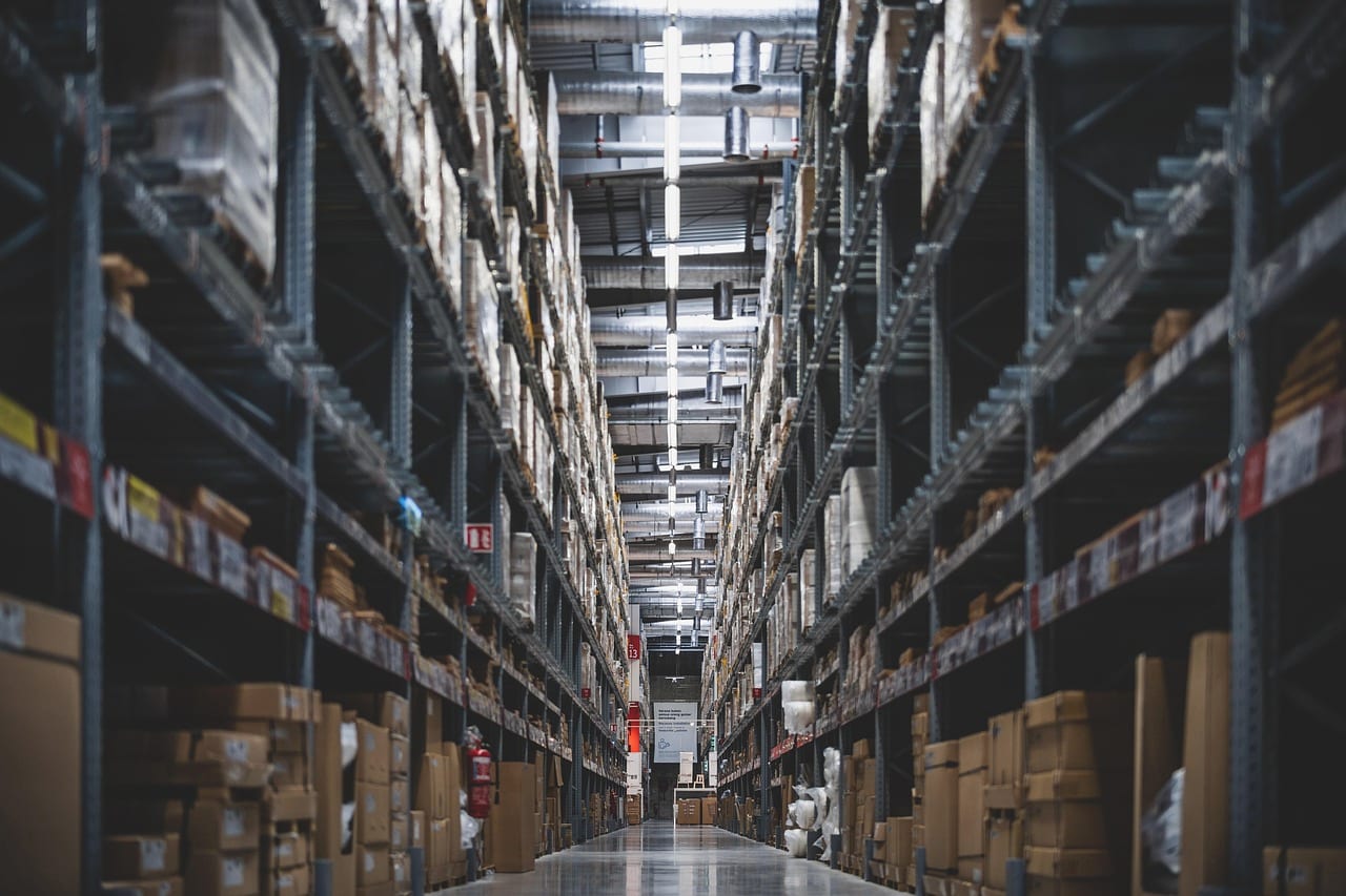 A narrow aisle between high racking in a dim warehouse