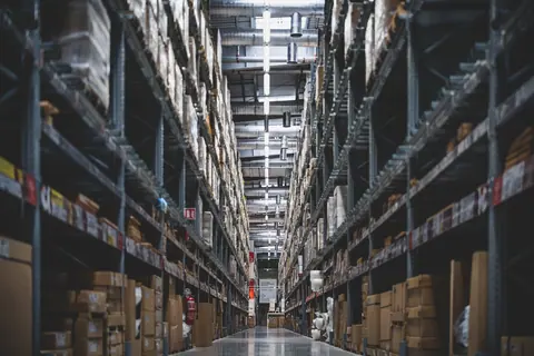 A narrow aisle between high racking in a dim warehouse