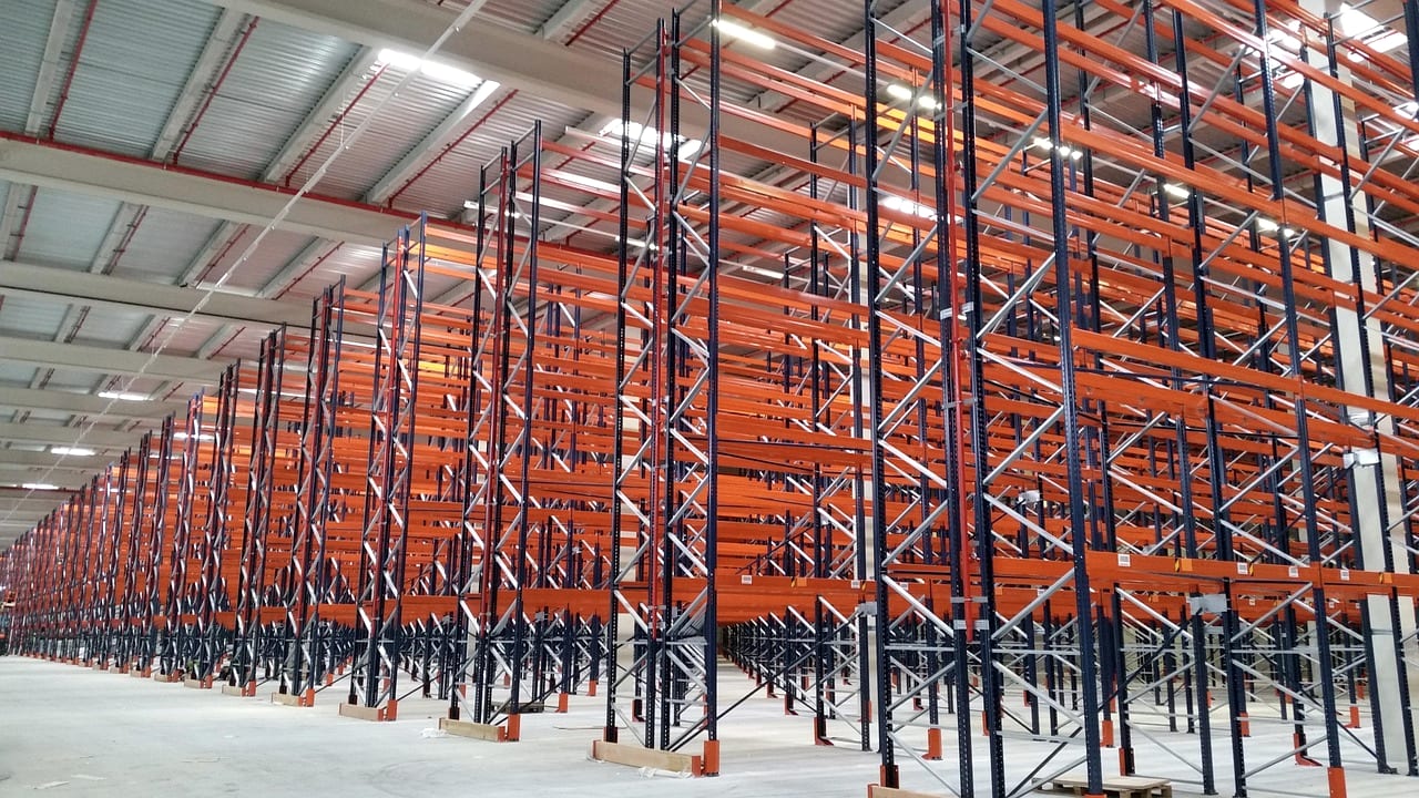 Empty orange pallet racking receding down a warehouse
