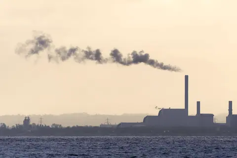 A single plume drifting from a stack across a pale evening sky
