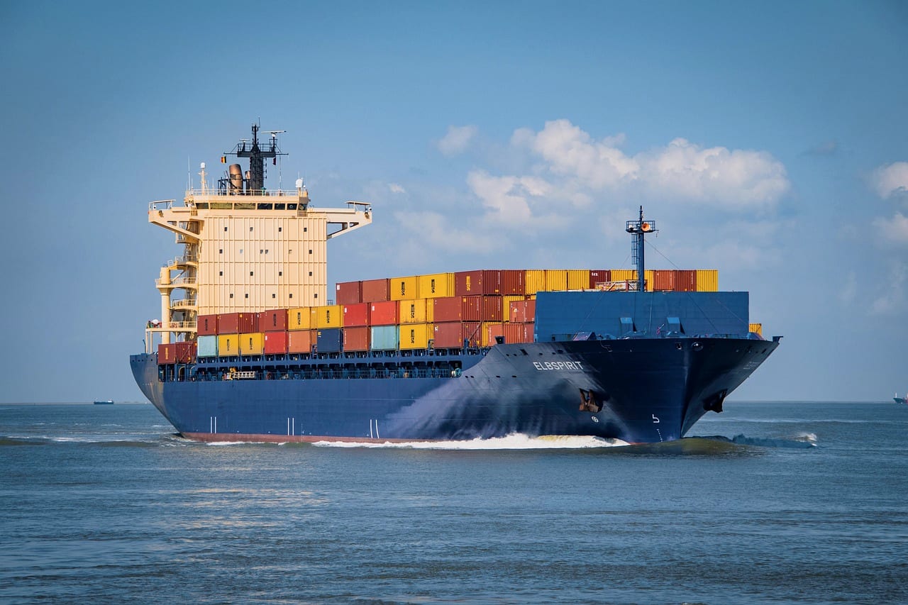 A container ship at sea, boxes stacked high on deck