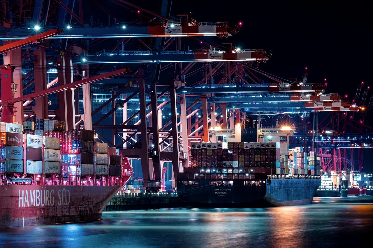 A container terminal working at night, cranes lit in red and blue