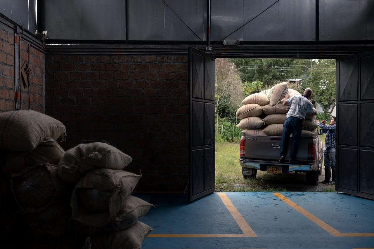 Sacks being unloaded from a pickup truck into a warehouse through open steel doors